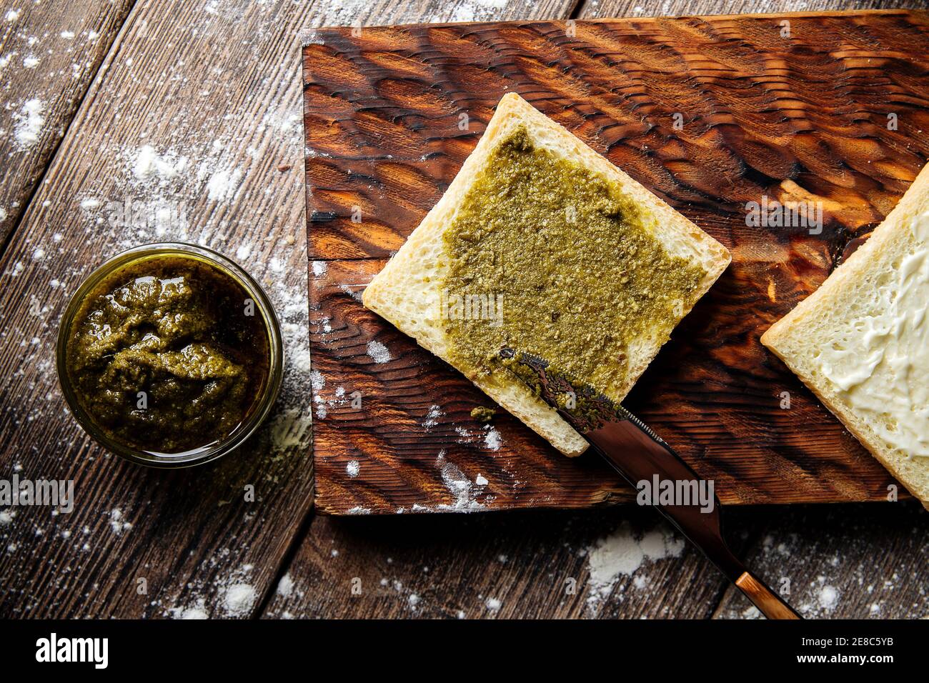 Spalmare la fetta di pane bianco con salsa al pesto Foto Stock