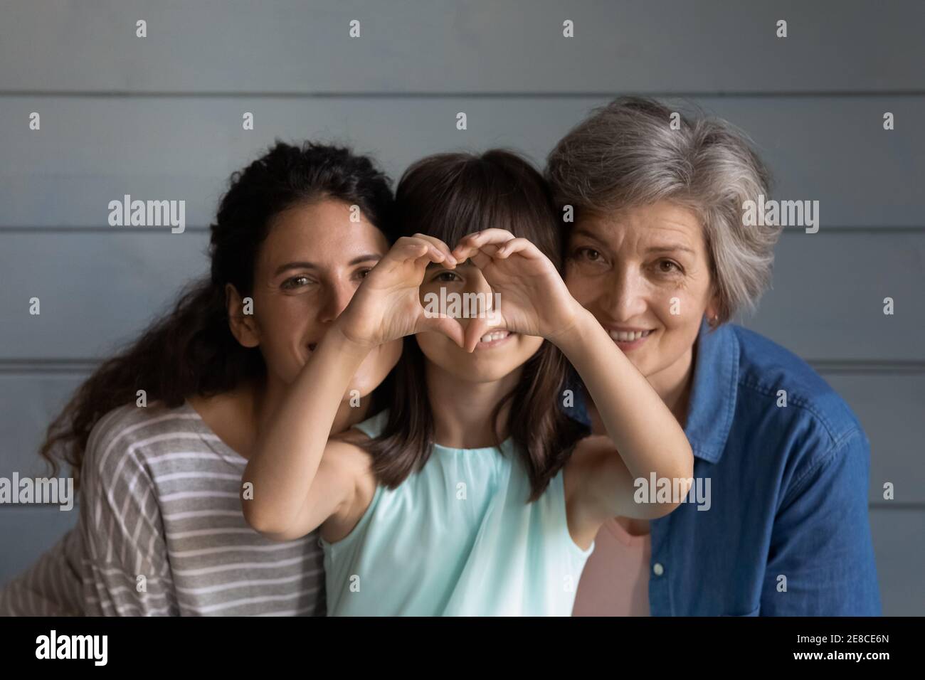 La testa ha girato la ragazza ritratto con la madre e la nonna che mostrano il cuore Foto Stock