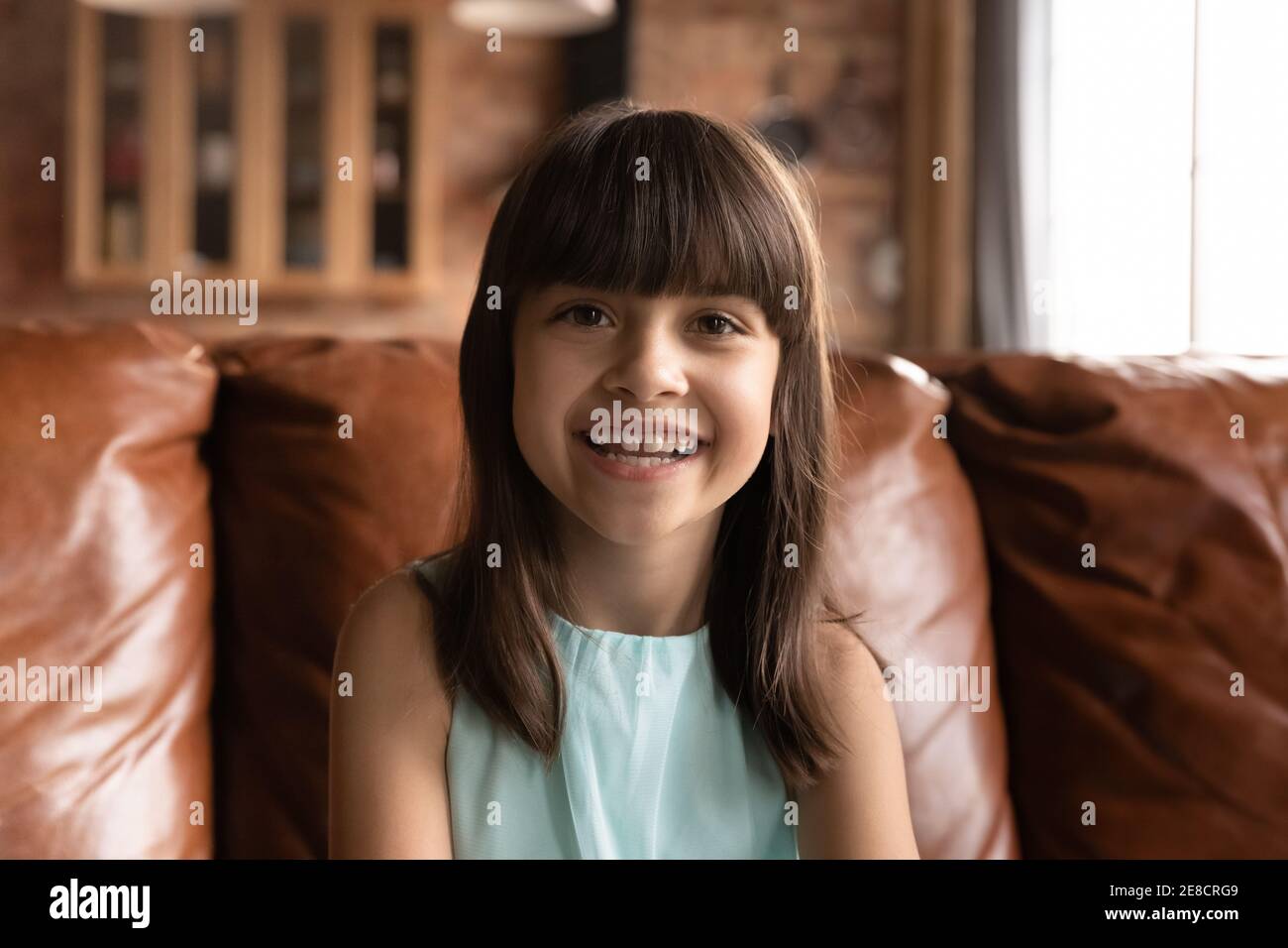 La testa ha girato il ritratto sorridente la bambina che parla alla macchina fotografica Foto Stock