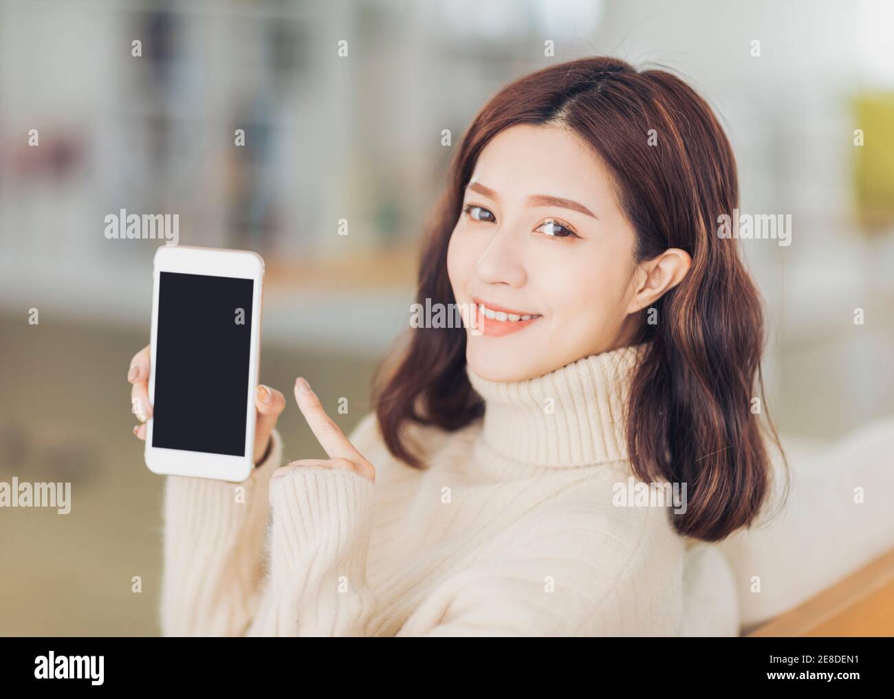 giovane donna che punta lo schermo vuoto dello smartphone a casa Foto Stock