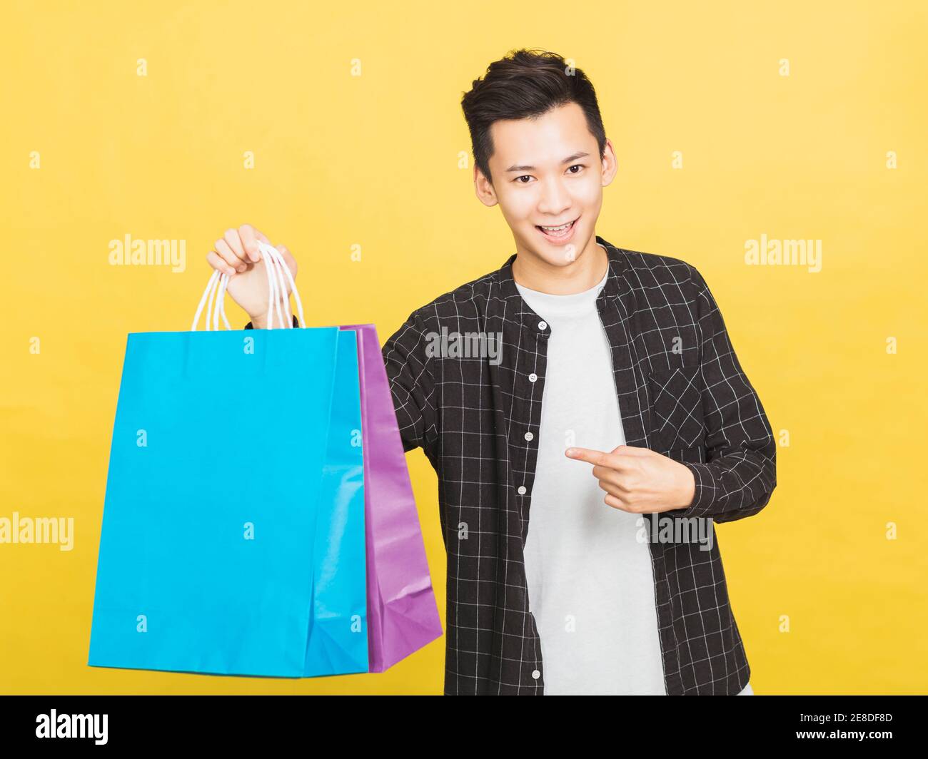 felice giovane uomo che mostra le borse della spesa Foto Stock