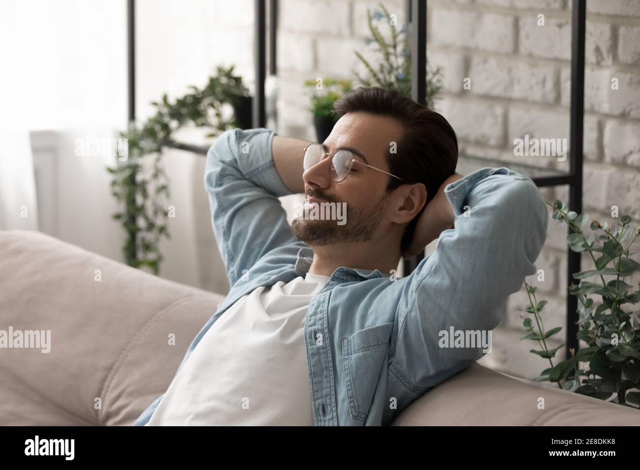 Primo piano uomo calmo indossare occhiali rilassante su un divano accogliente Foto Stock