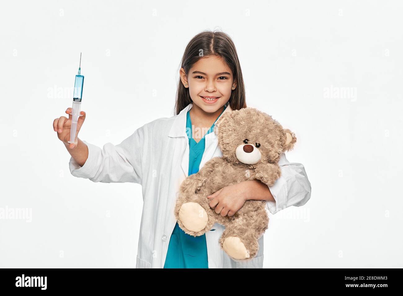 Latino American girl andando iniezione al suo paziente giocattolo dell'orso. Bambino che gioca medico veterinario, professione futura Foto Stock