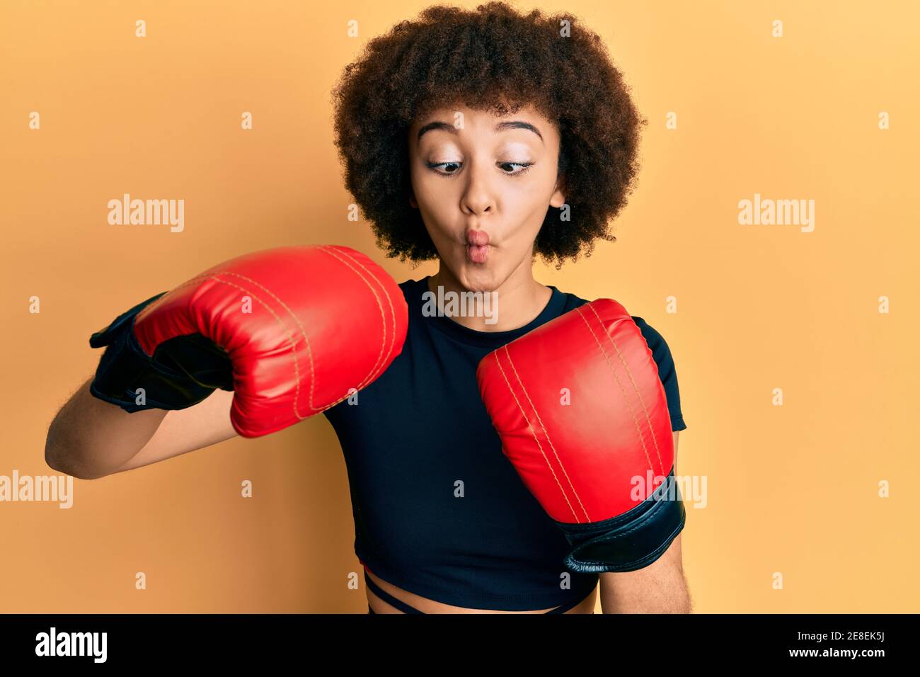 Giovane ragazza sportiva ispanica con guanti da boxe che fa viso di pesce  con bocca e occhi squinting, pazzo e comico Foto stock - Alamy
