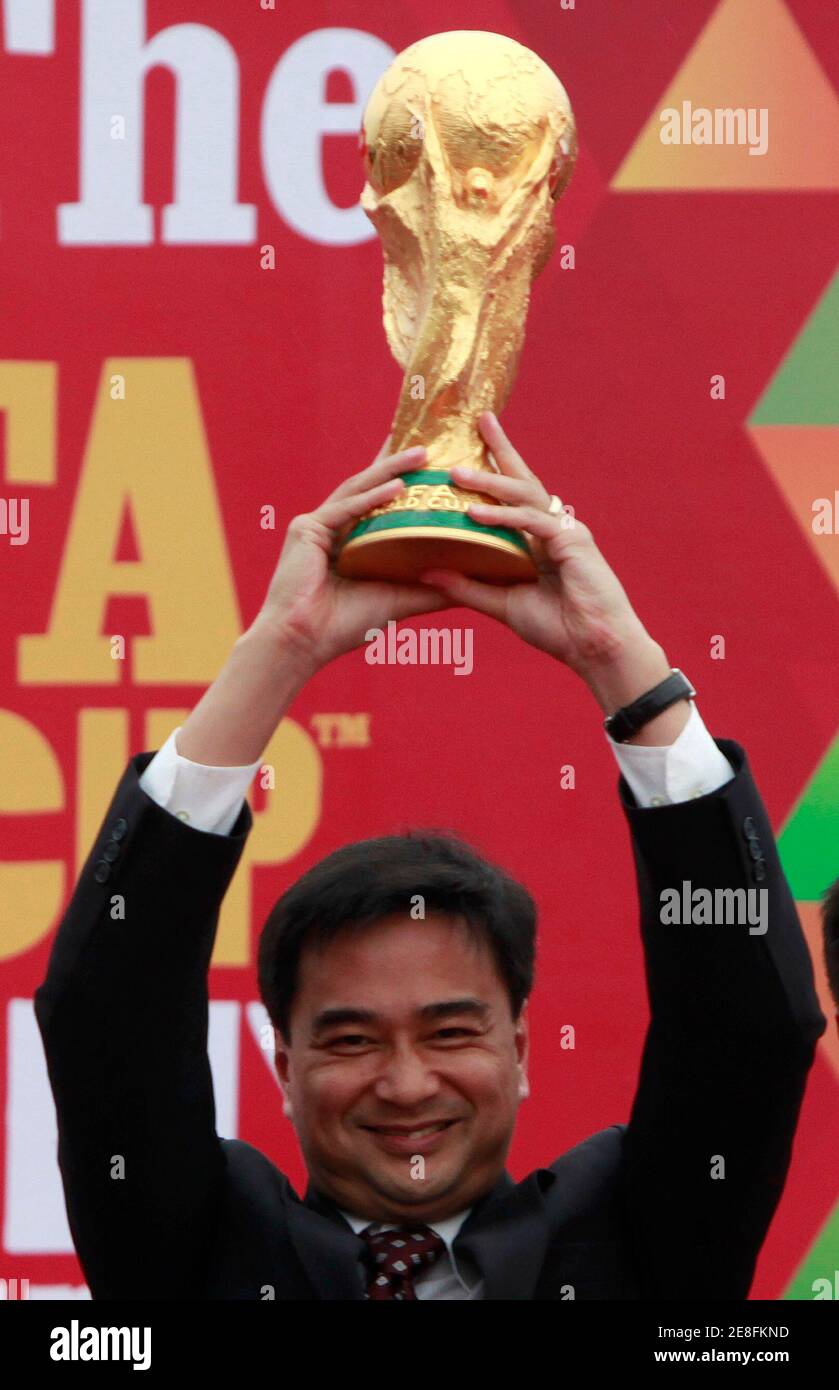 Il primo ministro tailandese Abhisit Vejjajiva tiene il trofeo della Coppa del mondo FIFA dopo essere arrivato all'aeroporto Don Muang di Bangkok il 21 gennaio 2010. Il trofeo sarà a Bangkok per tre giorni come parte del suo tour in giro per il mondo per gli appassionati di calcio. REUTERS/Chaiwat Subprasom (THAILANDIA - Tags: CALCIO SPORT) Foto Stock