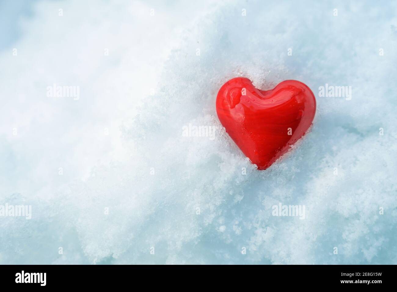 Forma del cuore in vetro rosso nella neve bianca fredda, simbolo dell'amore caldo per le feste stagionali come il giorno di valentine o chrismas, spazio di copia, selezionato fo Foto Stock