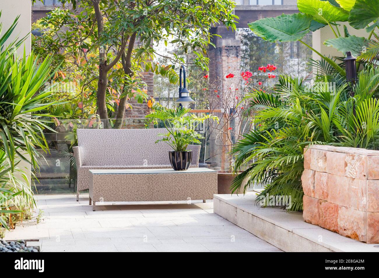Cortile con sedia di canna e tavolo in un giardino Foto Stock