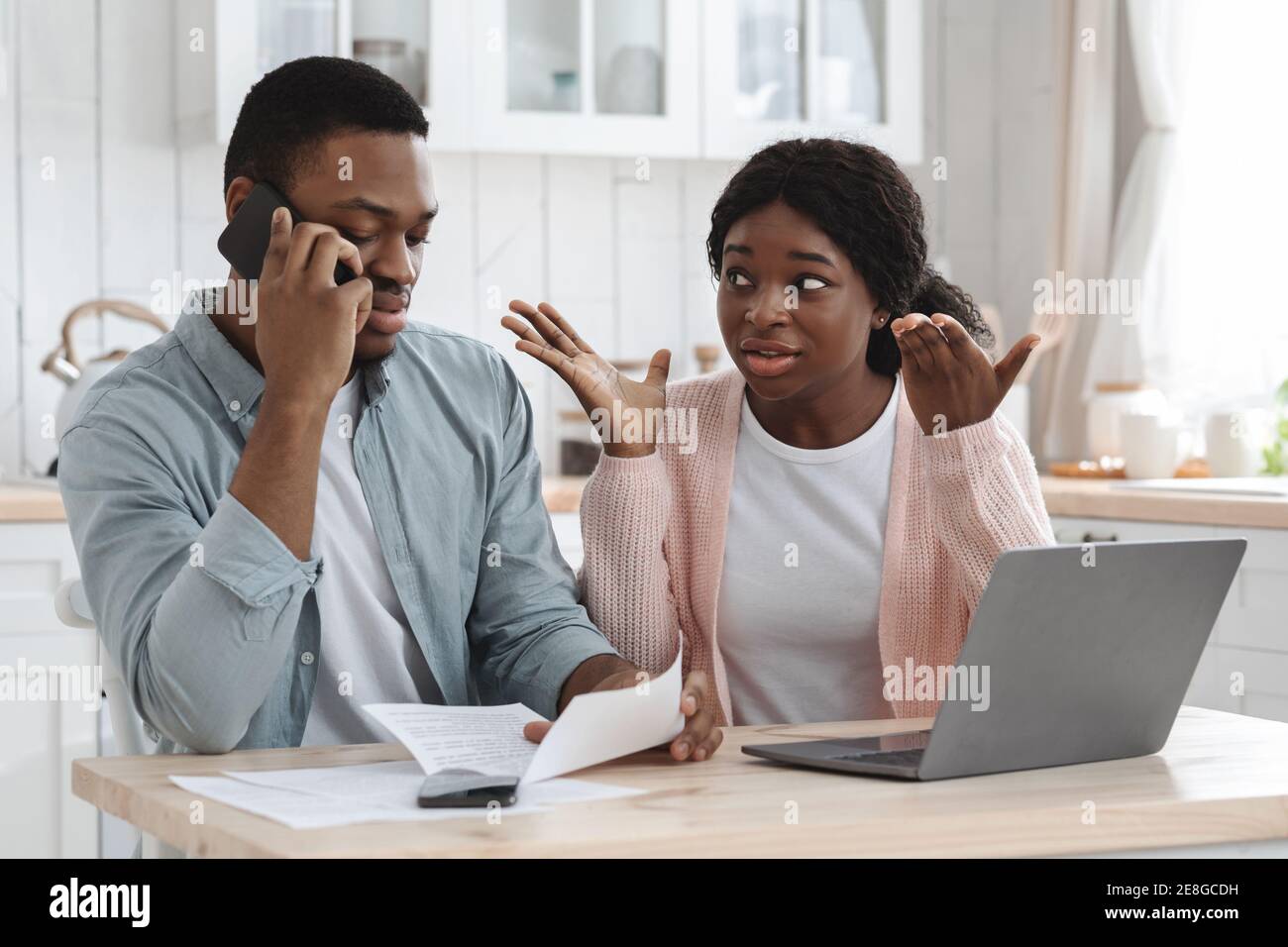 Worry Coppia nera seduta in cucina con i documenti finanziari, chiamando alla Banca Foto Stock