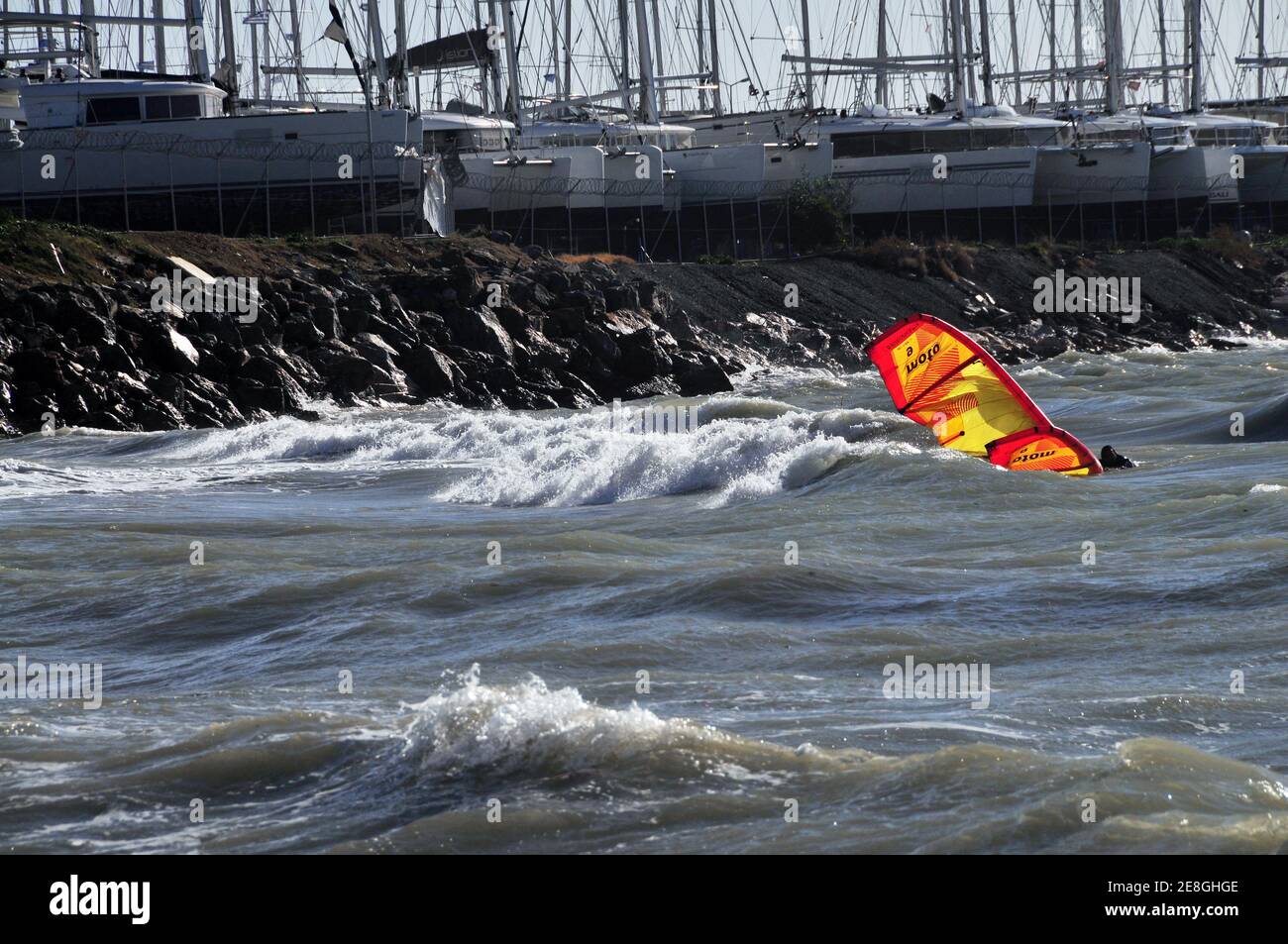 Caduta arancio e giallo aquilone surf in una giornata ventosa sulla costa di Atene, Grecia Foto Stock