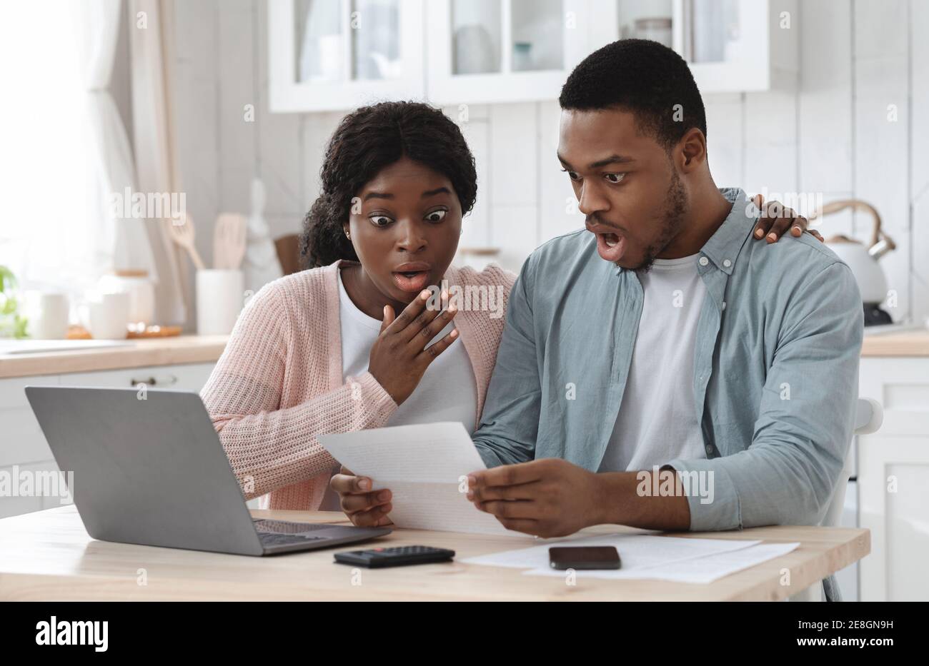 Scioccato coppia nera in cucina che ha problemi finanziari, facendo calcoli di bilancio di famiglia Foto Stock