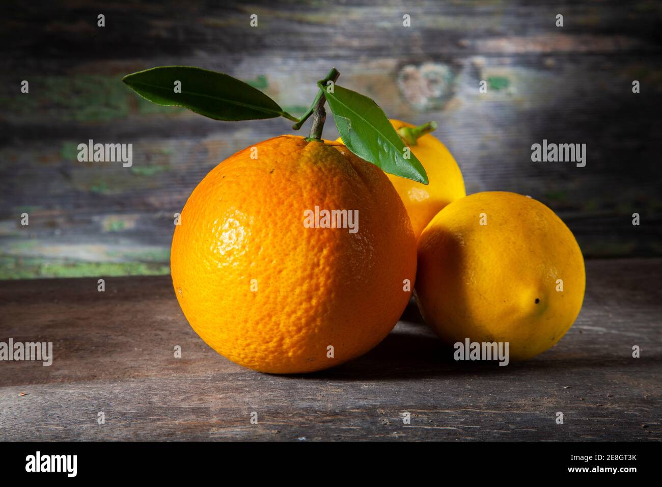 Autunno ancora vita di arancione e due limoni. Macro Foto di su tavola di legno con sfondo decaduto. Presa con Spotlight in Studio Foto Stock