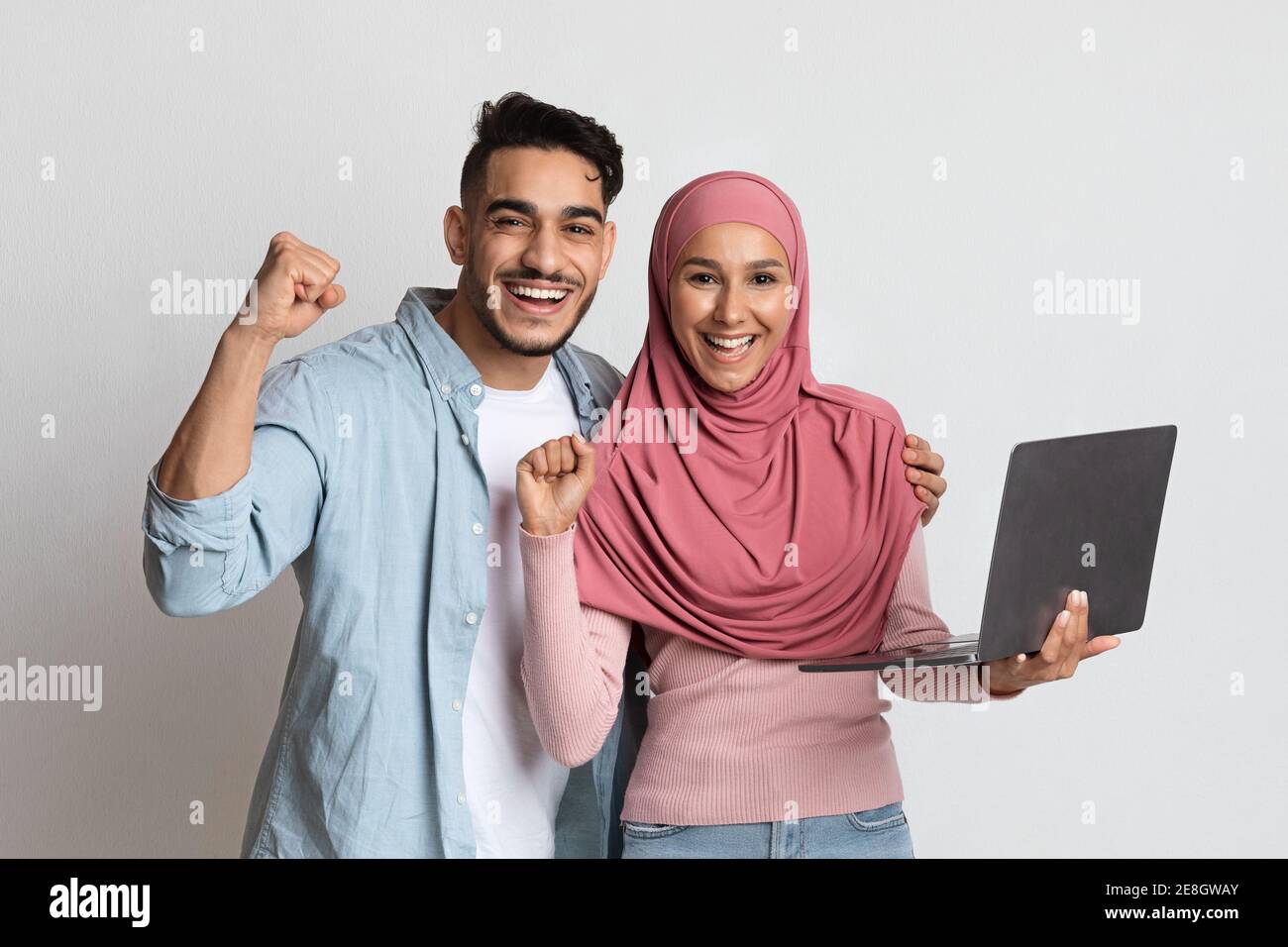 Fortunati vincitori. Coppia euforica musulmana che celebra il successo con il computer portatile Foto Stock