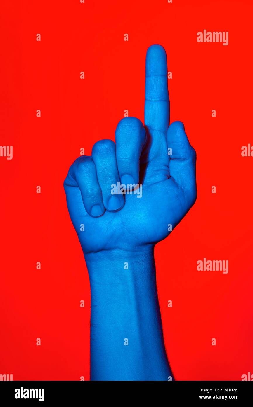 mano blu dell'uomo che fa il segno di numero uno sopra lo sfondo rosso. Foto verticale isolata Foto Stock