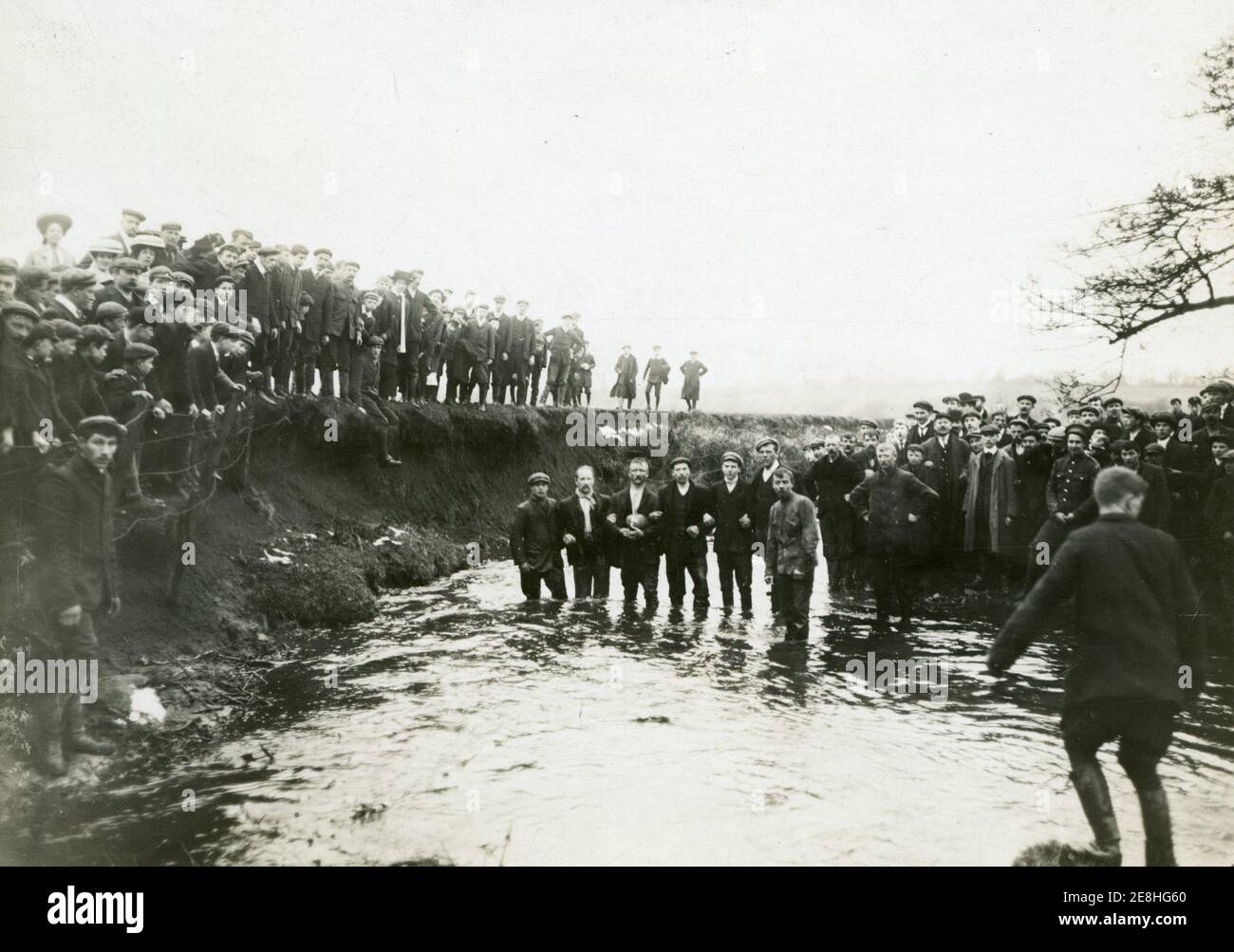 Ashbourne Shrovetide Football all'inizio del 20 ° secolo, probabilmente preso in entrambi gli anni '10 o '20, alcuni giocatori degli Up'ards nell'acqua del Henmore Brook e altri sulla banca a Sturston Mill avendo segnato un gol Foto Stock