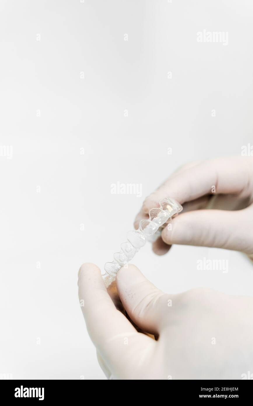 Coltivare dentista irriconoscibile in guanti in lattice con stecca in bianco background in clinica dentale Foto Stock