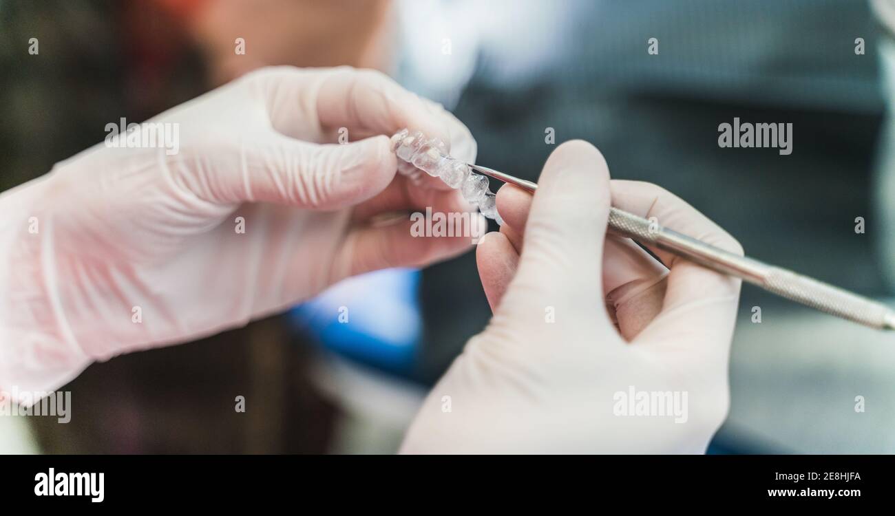 Coltivare dentista irriconoscibile in guanti in lattice con inserti ultra sottili e scaler mentre si lavora in clinica dentale Foto Stock