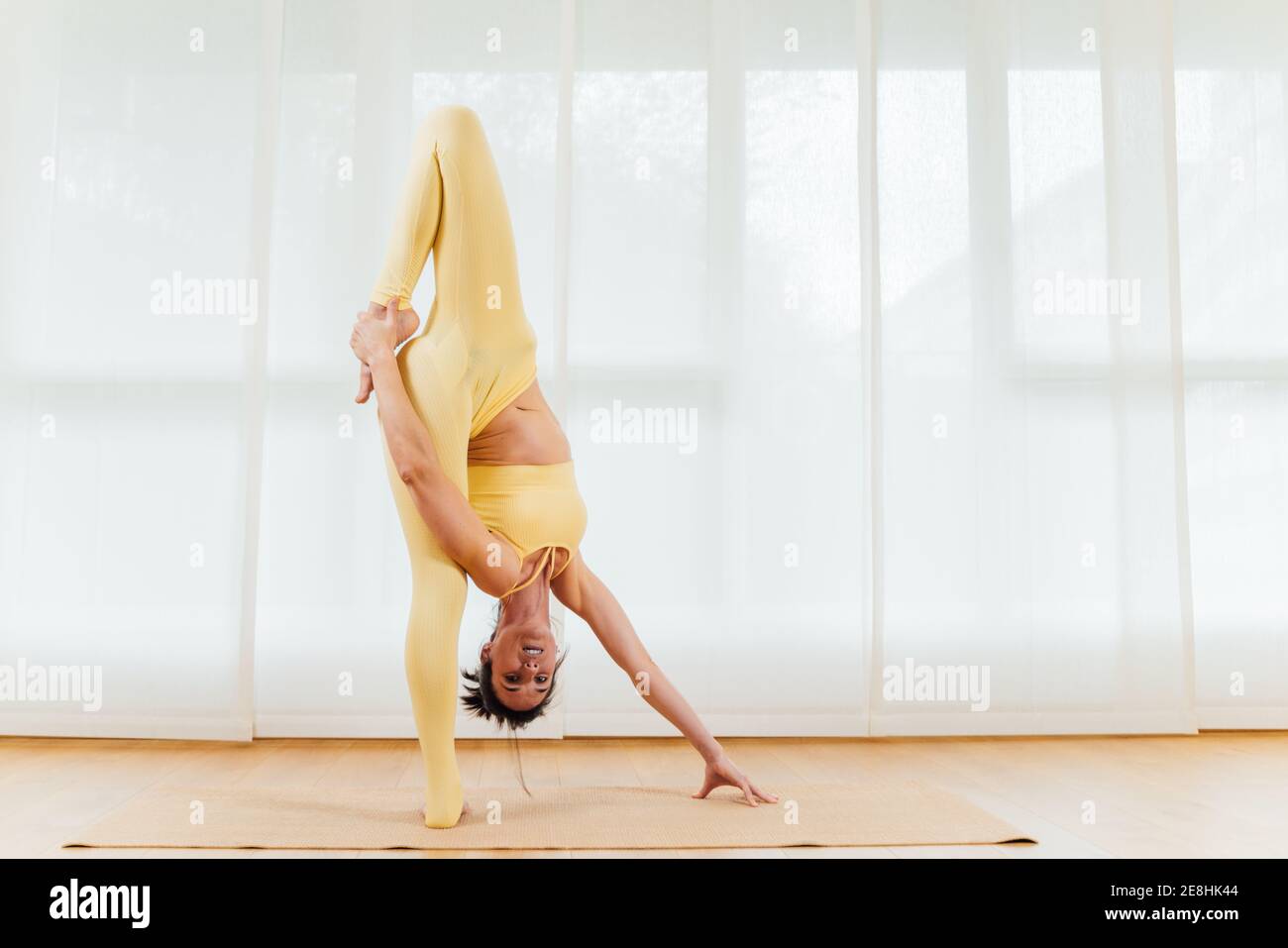 Vista laterale completa del corpo della femmina orientata che si piega in avanti con testa capovolta praticare yoga Foto Stock