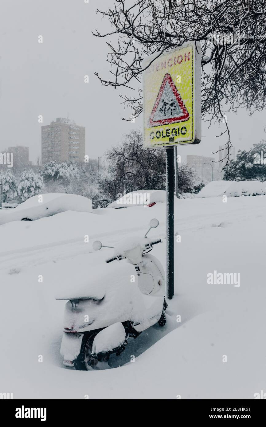 Moto contemporanea parcheggiata vicino al cartello stradale e coperta di spessore strato di neve nel sobborgo della città durante la gelida giornata invernale Foto Stock