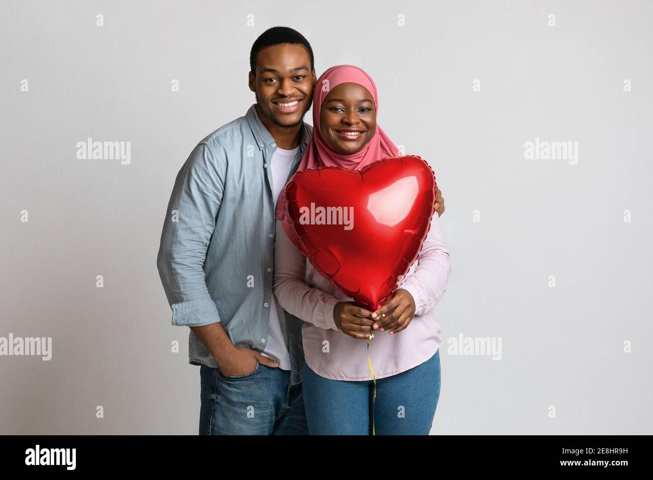 Gli amanti che tengono il palloncino a forma di cuore rosso e abbracciano Foto Stock