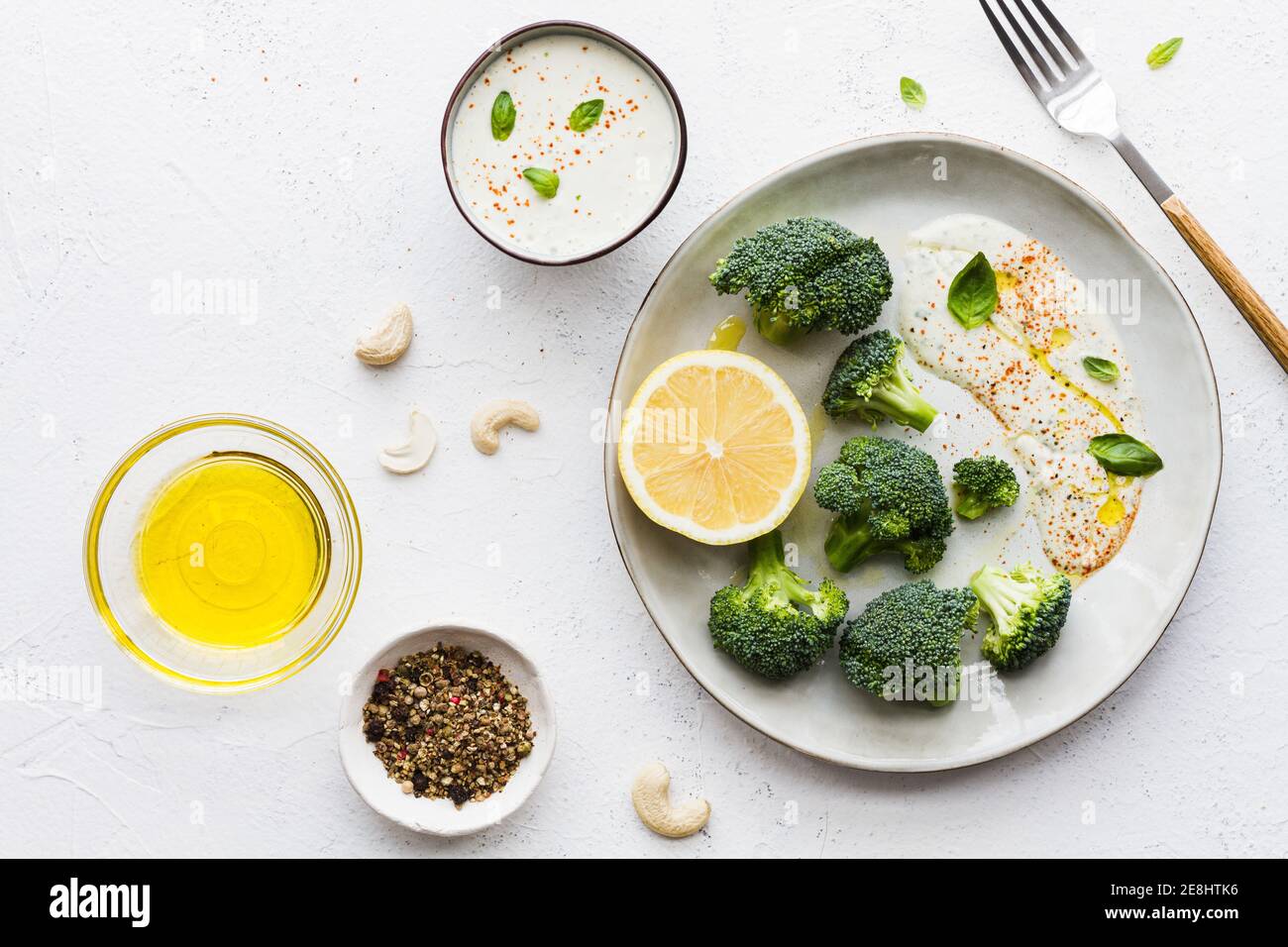Vista dall'alto dei gustosi broccoli con limone fresco e salsa vicino a ciotole con olio d'oliva e spezie mescolare sul tavolo Foto Stock