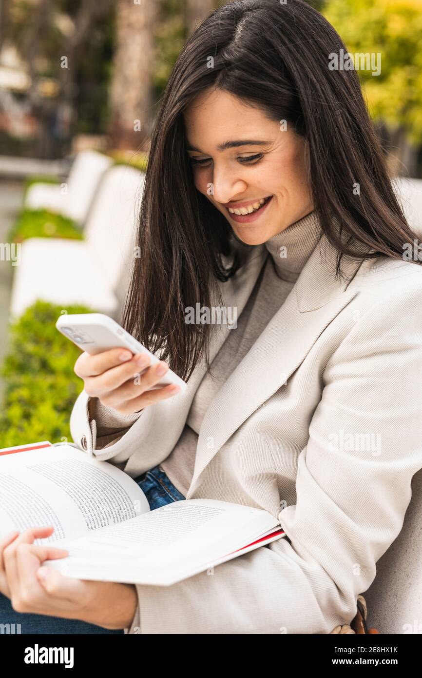 Sorridi l'imprenditore femminile utilizzando lo smartphone in strada mentre controlla i messaggi in e-mail Foto Stock