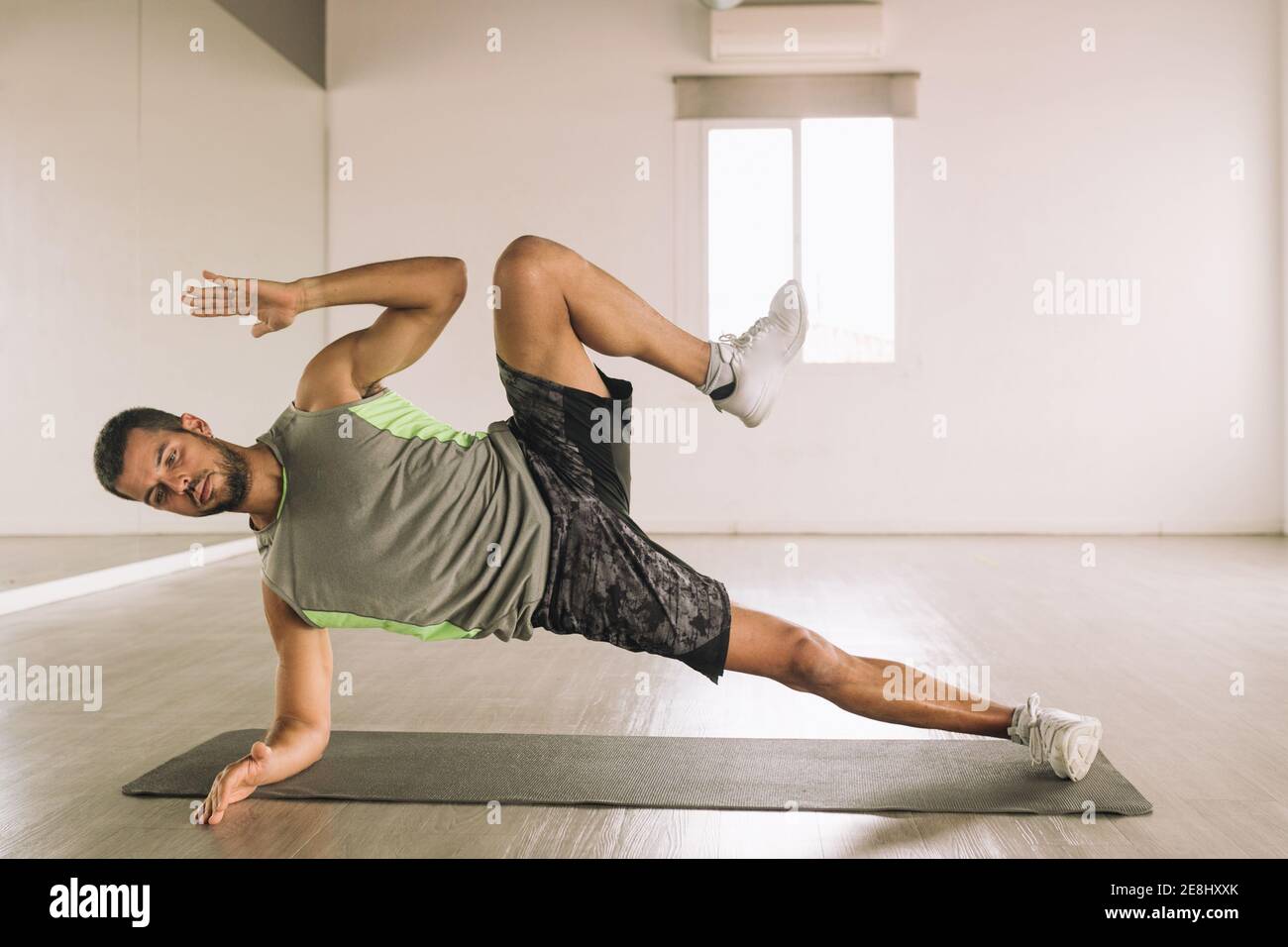 Corpo pieno di giovane sportivo in abbigliamento sportivo Esecuzione di High  Side Plank con gambe solleva esercizio durante l'allenamento in studio  vicino bi Foto stock - Alamy