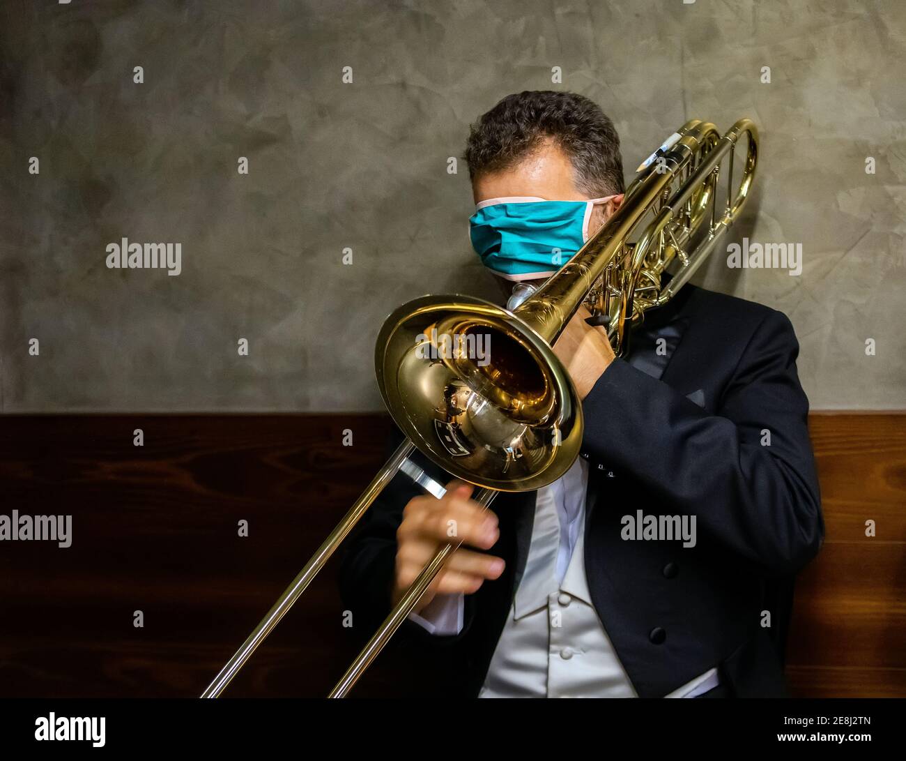 Musicista classico non identificato con trombone, indossando maschera prima del concerto nel backstage durante l'epidemia di Covid-19 Foto Stock