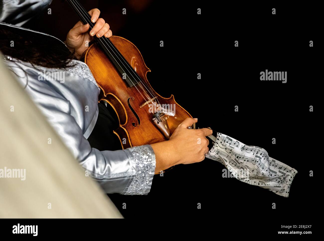 Musicista classico non identificato con violino e la sua maschera prima del concerto nel backstage durante l'epidemia di Covid-19. Foto Stock