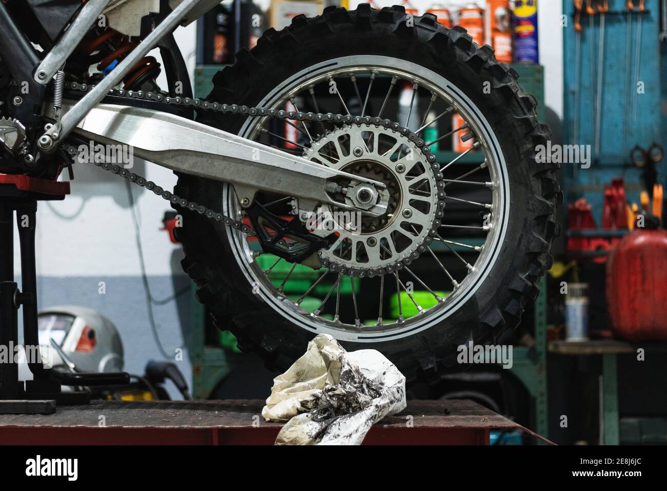 Ruota di moto d'epoca con dettagli cromati e catena posizionata su sollevatore a piattaforma durante la manutenzione in garage Foto Stock