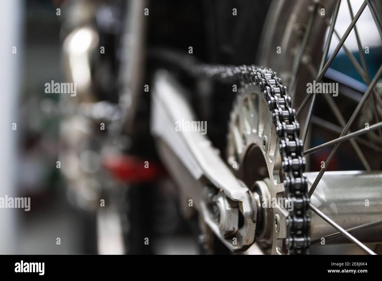 Ruota di moto d'epoca con dettagli cromati e catena posizionata su sollevatore a piattaforma durante la manutenzione in garage Foto Stock