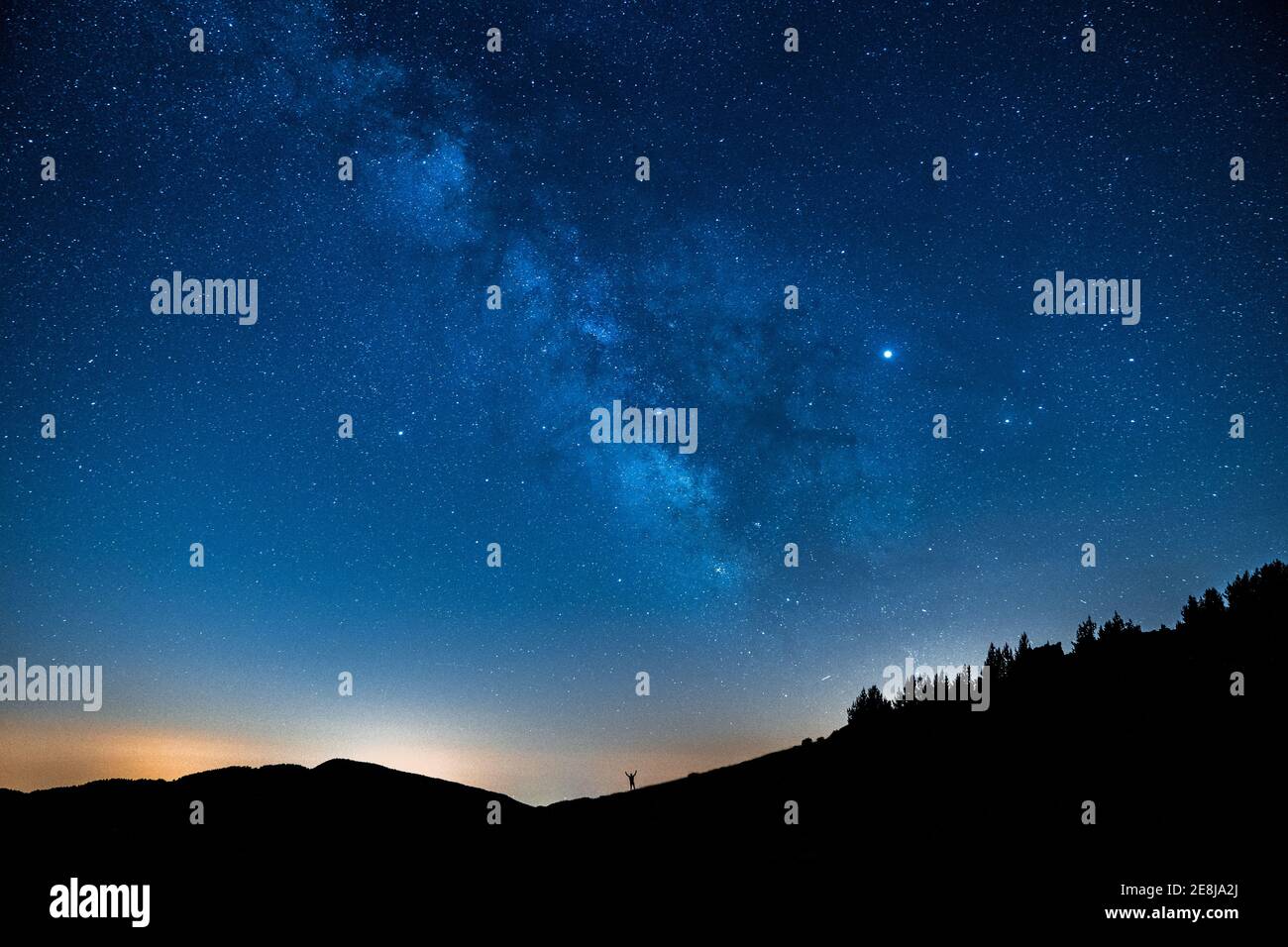 Vista pittoresca del cielo azzurro stellato con le nuvole sopra il monte con silhouette irriconoscibili al tramonto Foto Stock