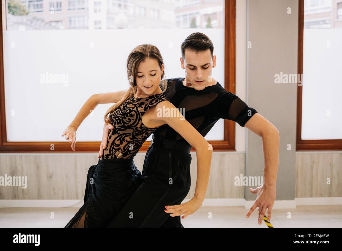 Coppia di ballerini di talento che si muovono con grazia mentre provano la danza da ballo in sala durante la lezione Foto Stock