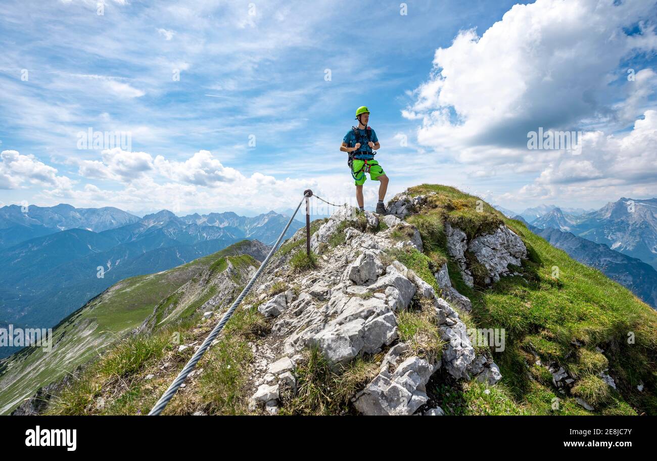Alpinista su una cresta su un percorso fisso di corda, Mittenwalder Hoehenweg, vista del panorama montano, Karwendel Montagne, Mittenwald, Baviera Foto Stock