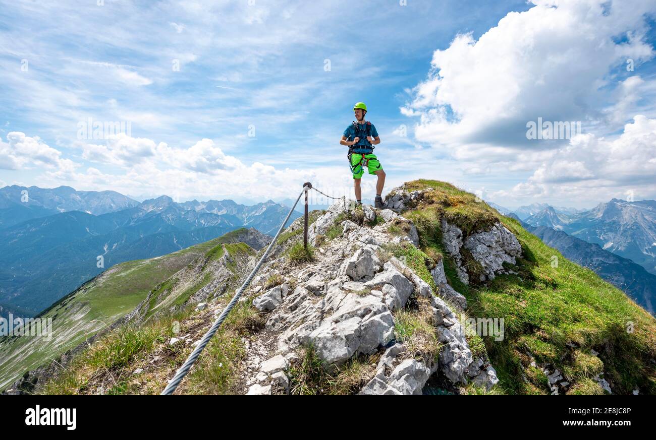 Alpinista su una cresta su un percorso fisso di corda, Mittenwalder Hoehenweg, vista del panorama montano, Karwendel Montagne, Mittenwald, Baviera Foto Stock