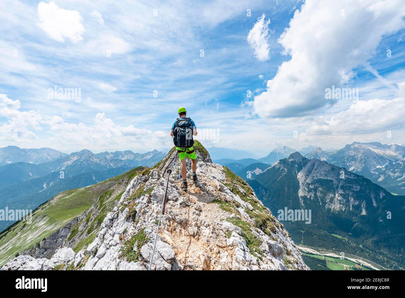 Alpinista su un crinale su una ferrata sicura, Mittenwalder Hoehenweg, vista sulla valle dell'Isar vicino a Mittenwald, Karwendel Mountains, Mittenwald Foto Stock