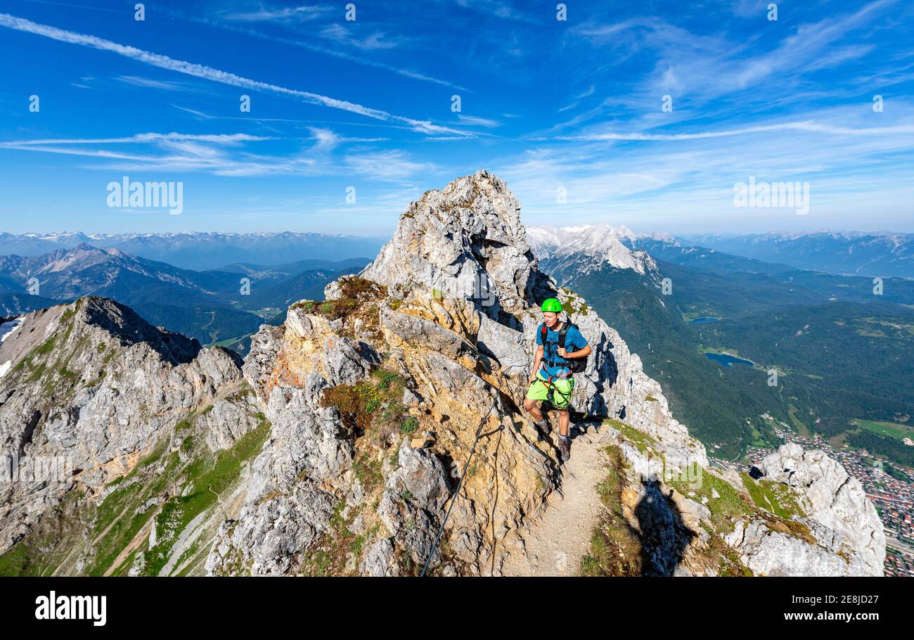 Alpinista su un crinale su una ferrata sicura, Mittenwalder Hoehenweg, vista sulla valle dell'Isar vicino a Mittenwald, Karwendel Mountains, Mittenwald Foto Stock