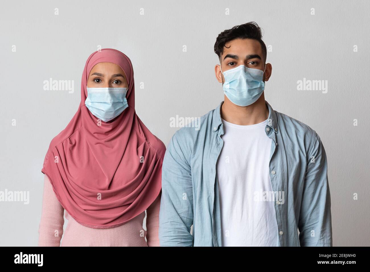 Concetto di impatto del coronavirus. Ritratto di una coppia musulmana seria in maschere mediche protettive Foto Stock