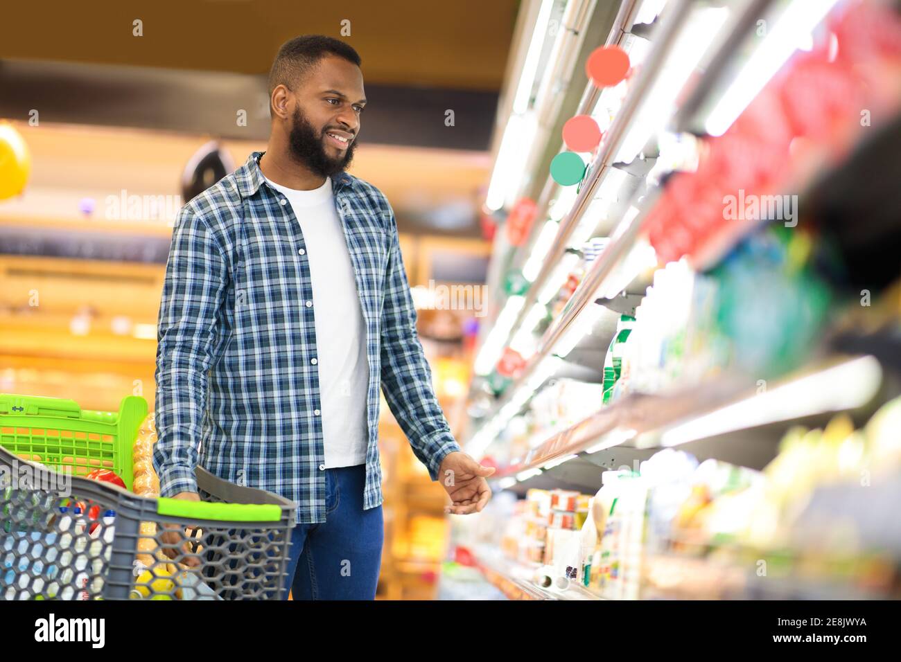 Afroamericano Guy Comprare cibo in piedi vicino Shelf in supermercato Foto Stock