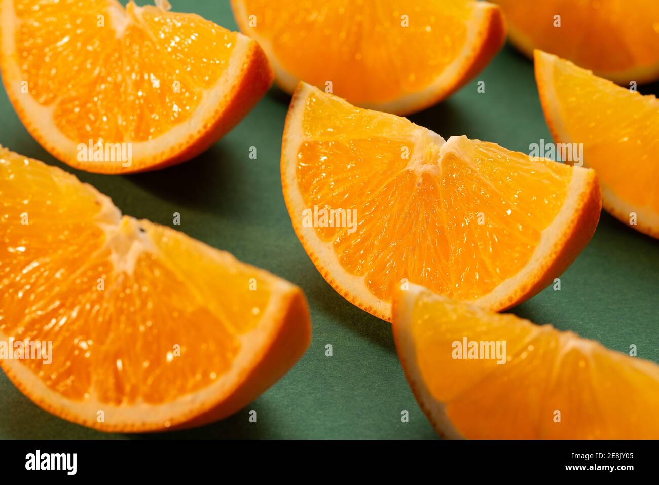 Fette di arancio fresco su sfondo verde brillano nei raggi del sole della sera. Foto Stock