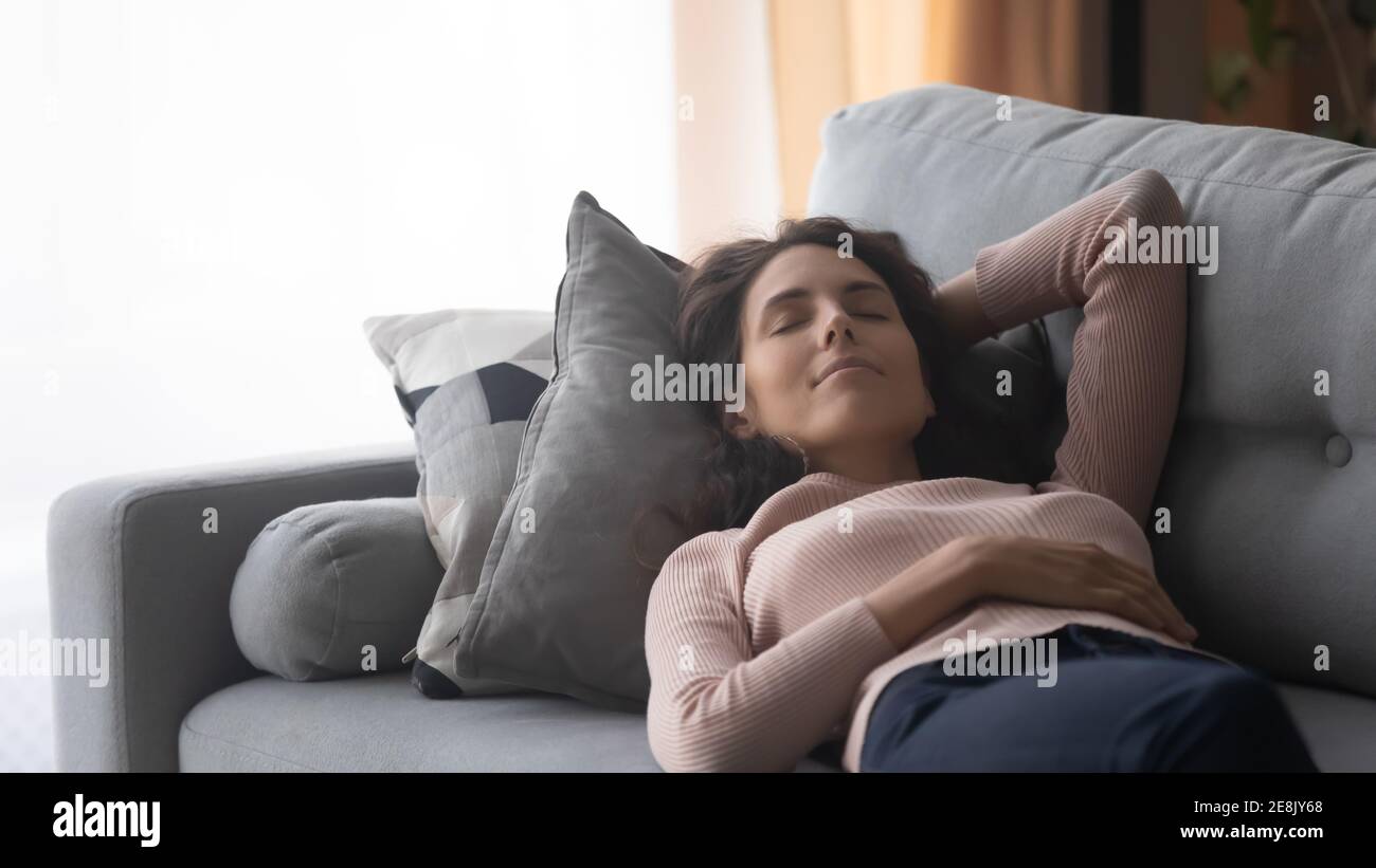 Donna millenaria rilassata che dorme su un comodo divano. Foto Stock