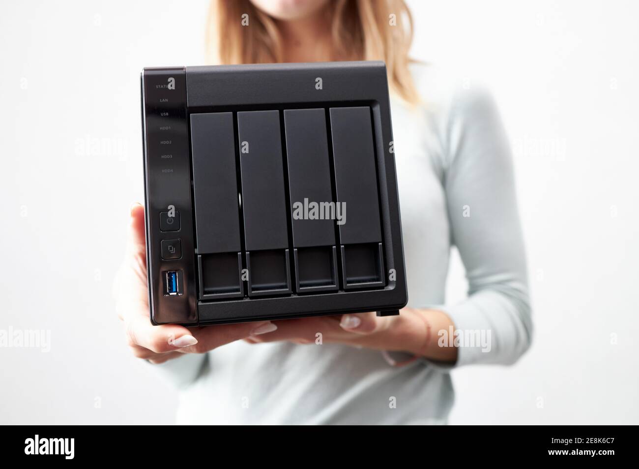 la ragazza tiene in mano un ufficio portatile o un server nas di dati domestici. dispositivo per il backup di informazioni importanti. spazio di copia. Foto Stock