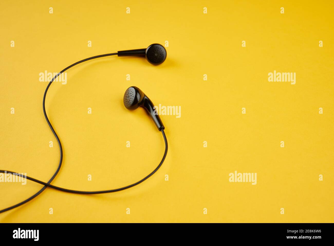 auricolari neri isolati su uno sfondo giallo caldo alla moda. stile di vita musicale. spazio per la copia. disposizione piatta Foto Stock