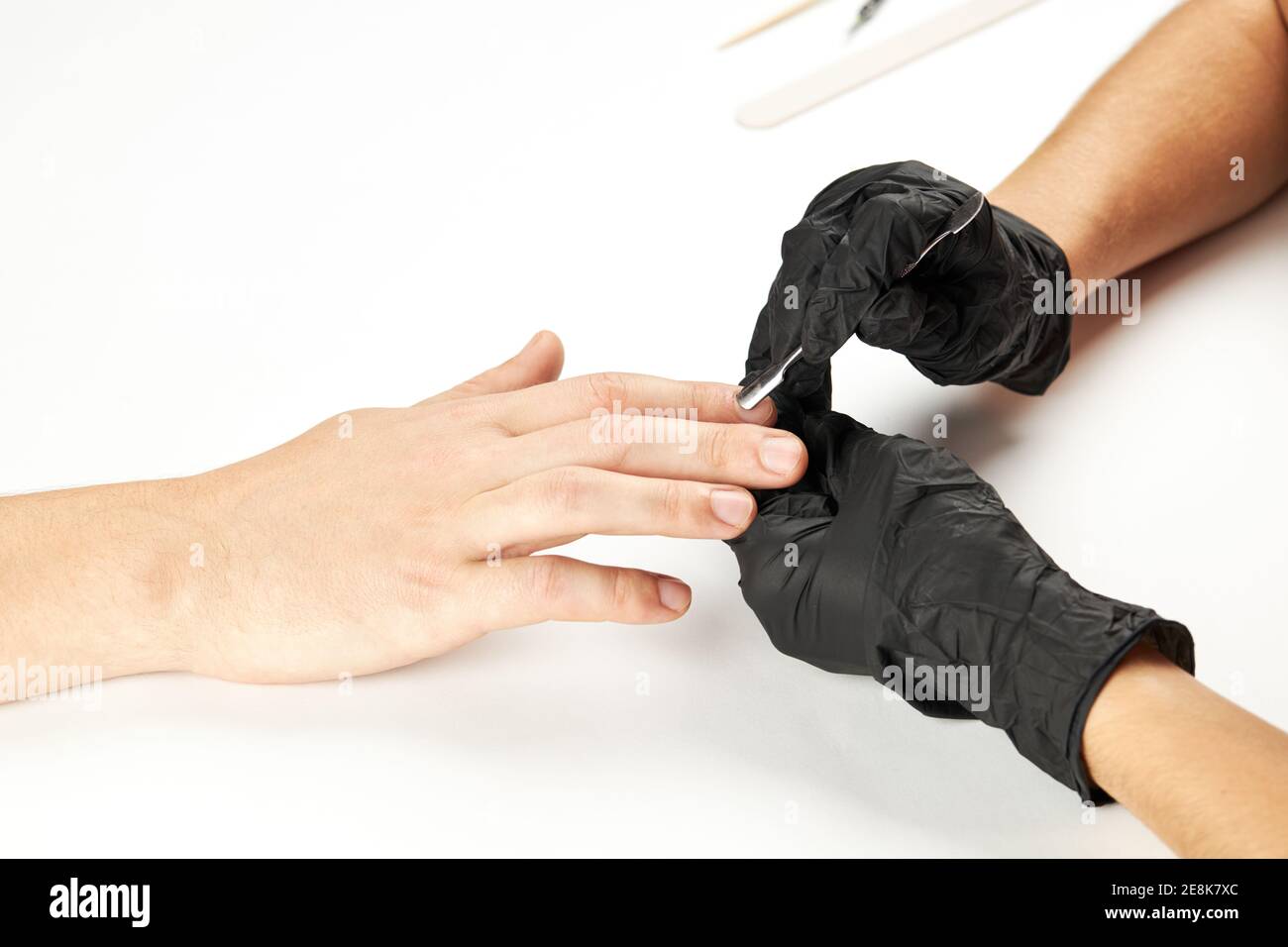 manicurista durante il lavoro con il bastone di metallo del chiodo. un processo di manicure dell'uomo. una persona caucasica irriconoscibile che fa il servizio del chiodo al salone di cure estetiche. Foto Stock