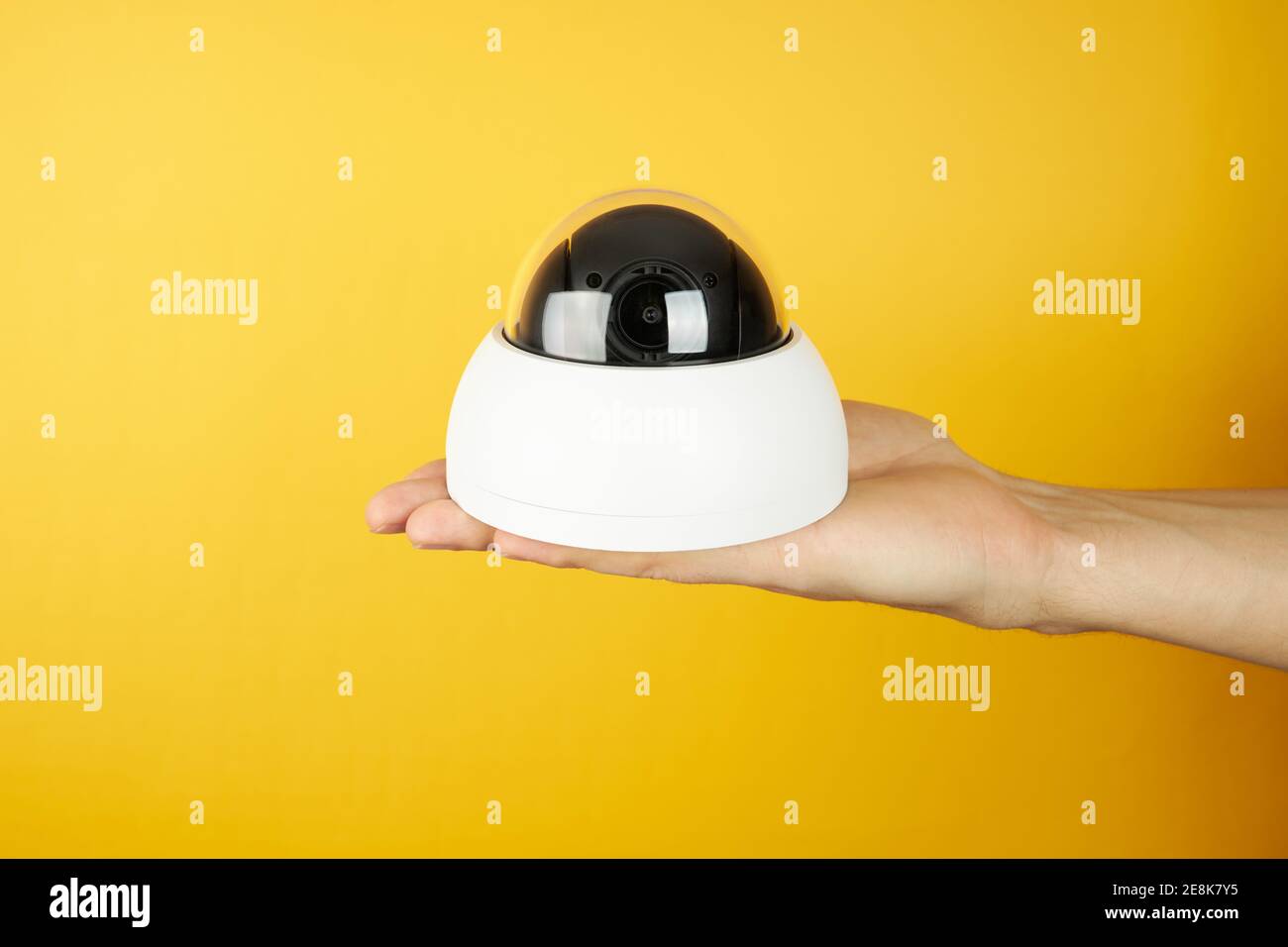 Telecamera di sorveglianza tvcc di attesa sul palmo di un palmo su sfondo giallo con spazio di copia. Concetto di sicurezza e privacy Foto Stock