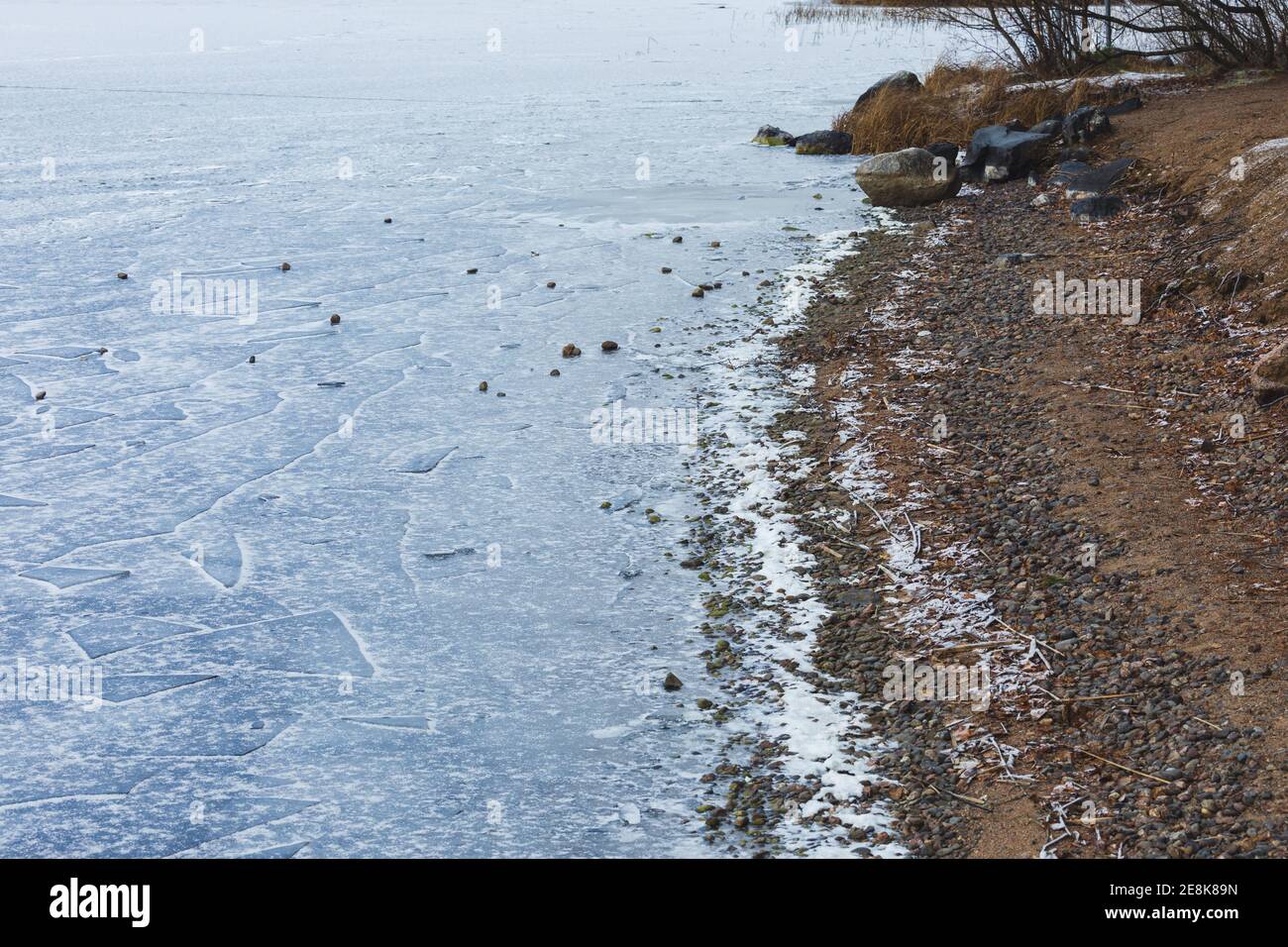 Lago ghiacciato riva e neve durante il giorno d'inverno Foto Stock