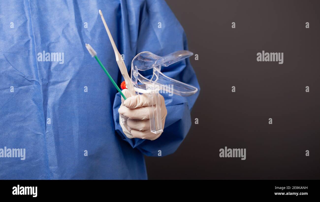Una dottoressa è una ginecologa in una rosa blu. Accessori ginecologici,  specchio venus, spazzola, bastone. Sfondo grigio, spazio vuoto per il testo  Foto stock - Alamy