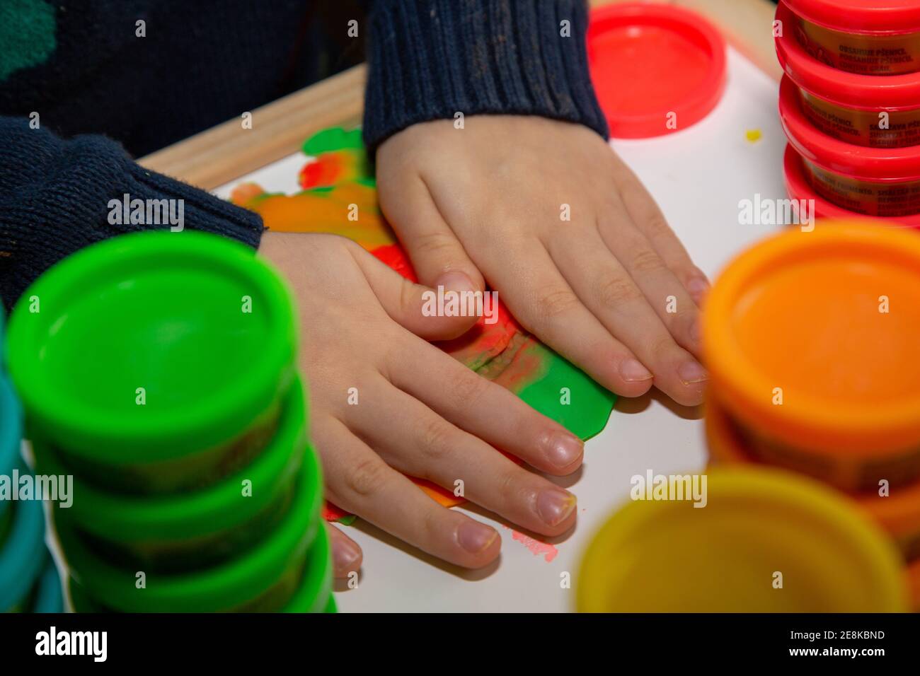 Un bambino che gioca con Play Doh modellando l'argilla a un tabella Foto Stock