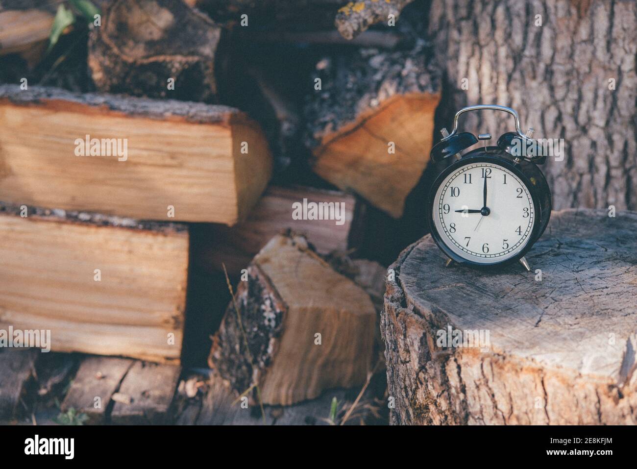 una vecchia sveglia impostata a dodici e una stella su una superficie rustica in legno e legna da ardere. Foto Stock