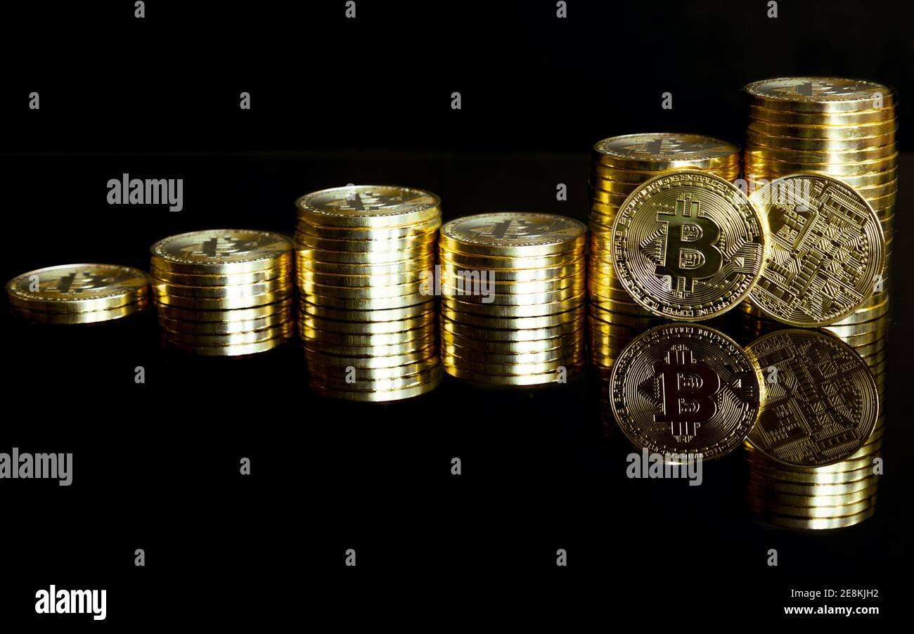 Monete d'oro impilate come un grafico. Con riflessione su sfondo nero. Foto Stock