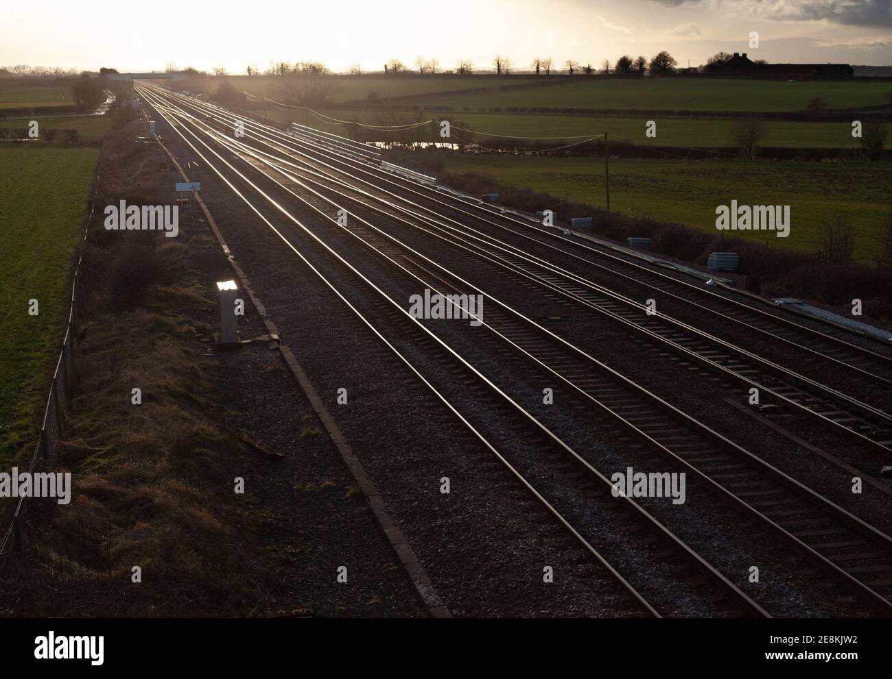 Vista serale delle piste ferroviarie della costa orientale Linea principale nello Yorkshire con luce solare dorata che si riflette rotaie Foto Stock